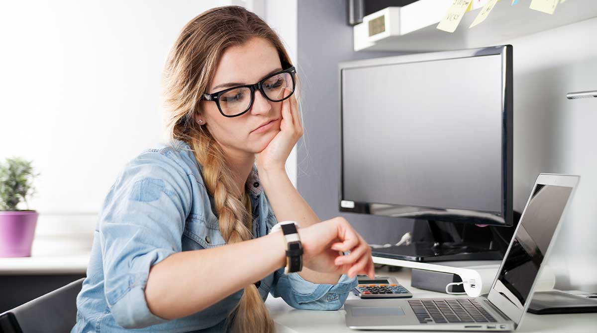 Bored Female Employee checks her watch at desk